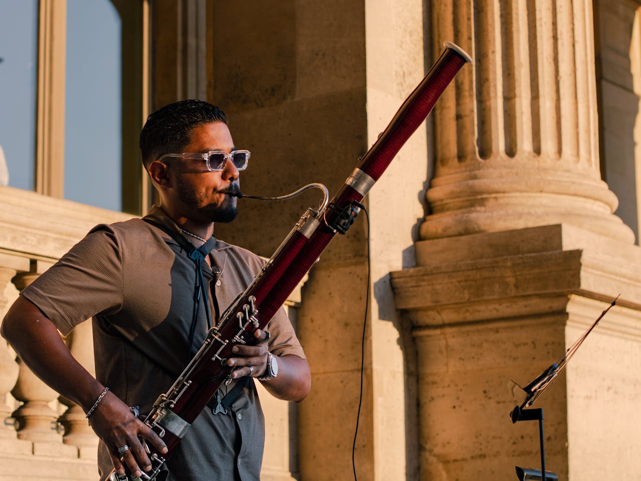 Musician playing bassoon outdoors on a sunny day, showcasing musical talent.